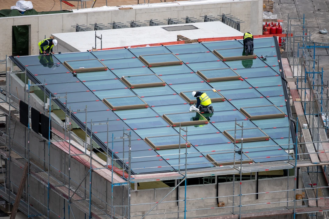 Roofer installing windows for a light well on the roof of a commercial building